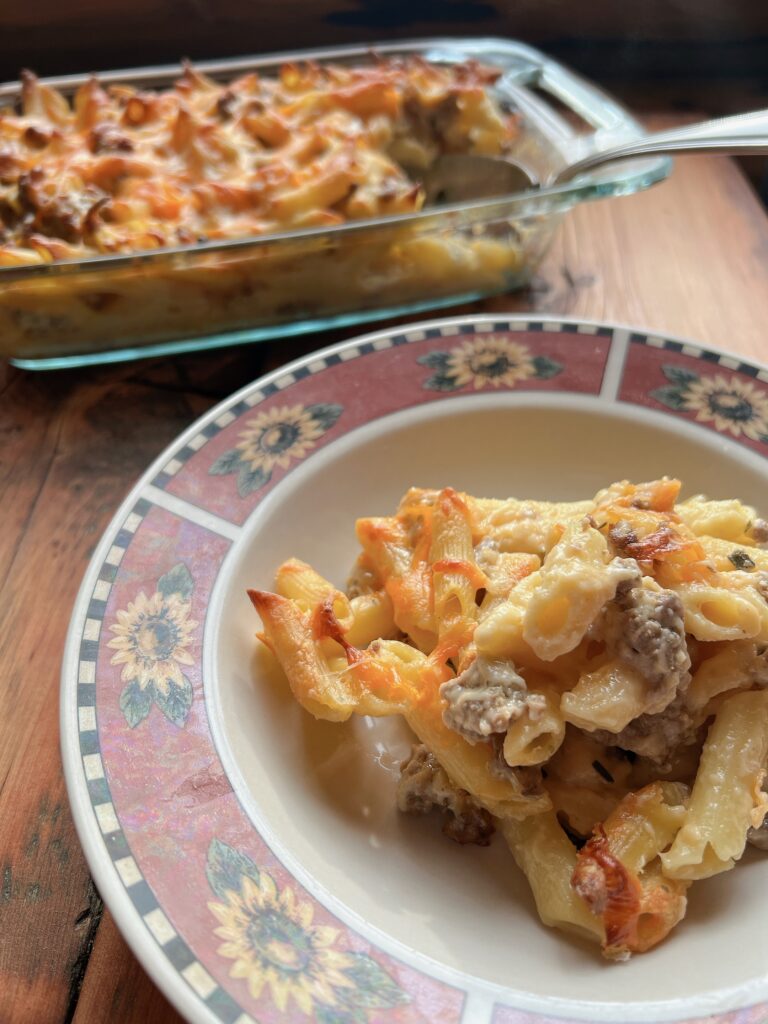 A white plate with a sunflower design that has a pile of sausage kale pasta with 20 minute creamy white sauce recipe on it.