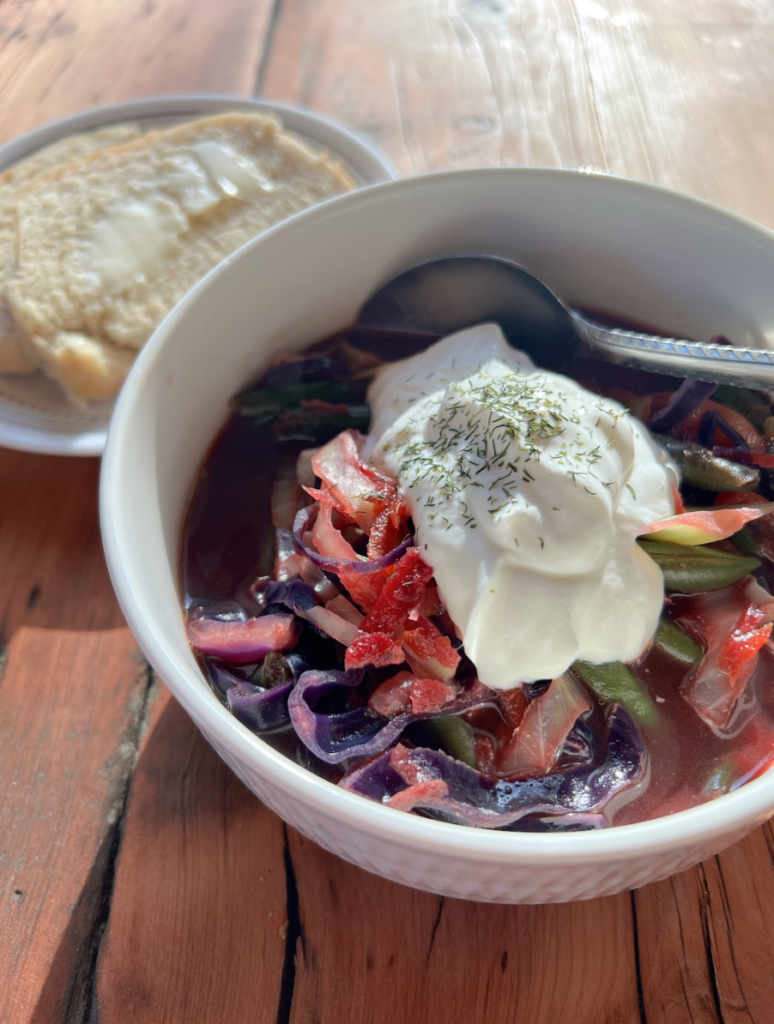 A bowl of simple vegetable beet borscht topped with sour cream.