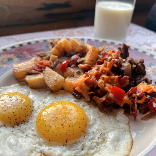 Baked Crispy Hashbrown Casserole on a plate with two sunny side up eggs.