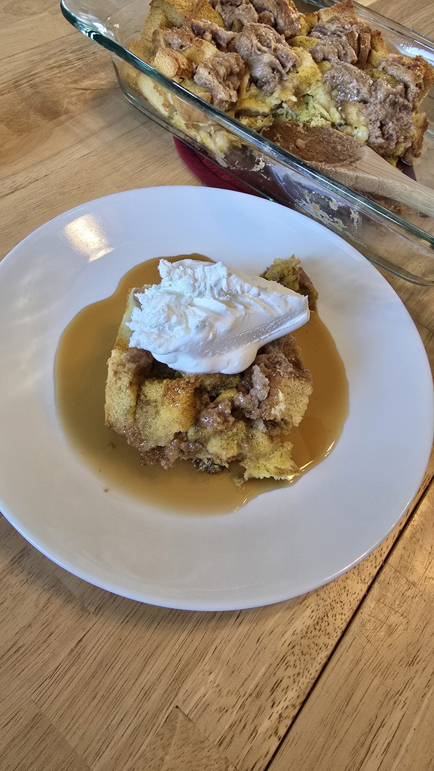 A white plate with pumpkin spice baked french toast casserole topped with whipped cream.