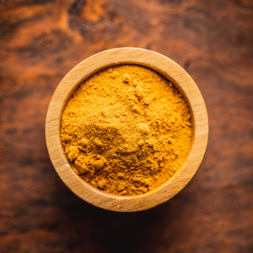 A wooden bowl tilled with homemade pumpkin pie spice on a wooden counter.