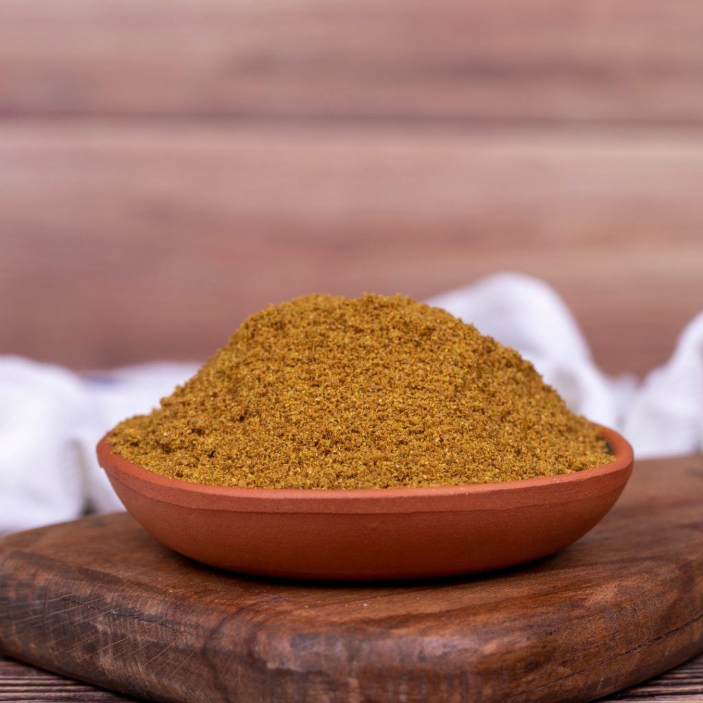 A wooden bowl full of homemade chili seasoning.