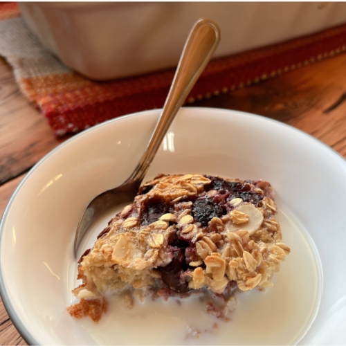 A bowl of cherry almond baked oatmeal served with milk and a spoon, highlighting a healthy, meal-prep-friendly breakfast.