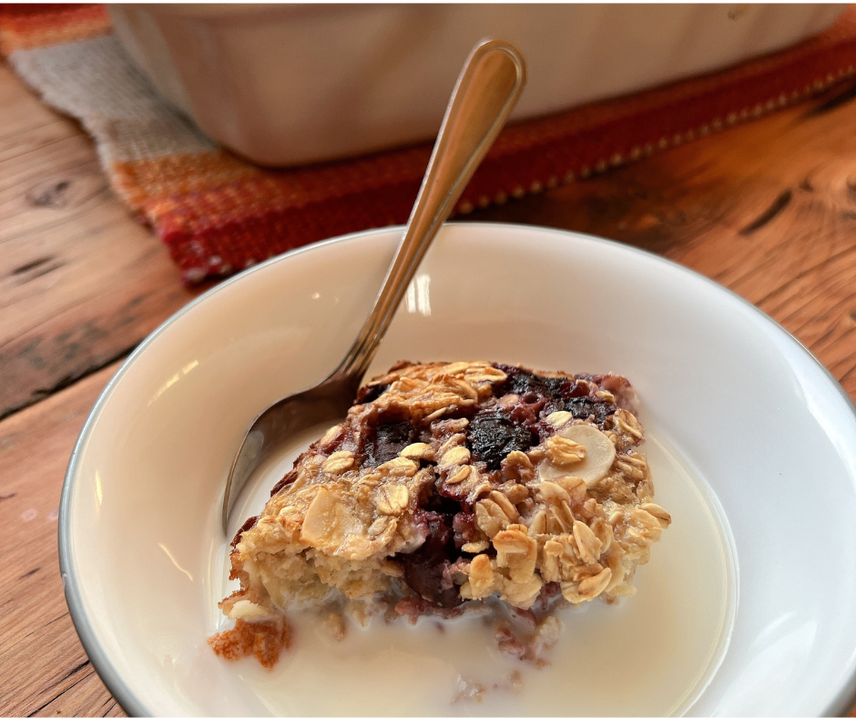 A bowl of cherry almond baked oatmeal served with milk and a spoon, highlighting a healthy, meal-prep-friendly breakfast.