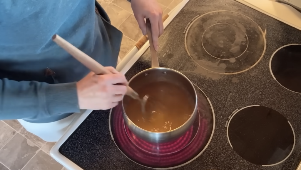 Stirring gelatin into water in a pot on the stove to make jello.