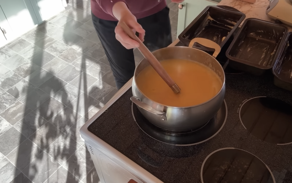 Stirring cornmeal into liquid in a pot to make cornmeal mash.