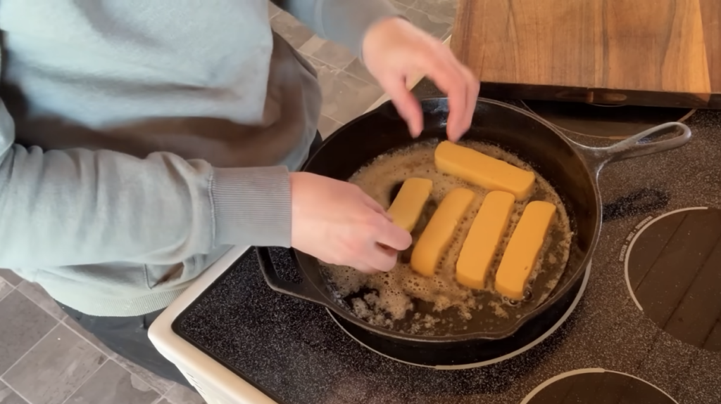 Frying sticks of cornmeal mash in a cast iron skillet with butter.
