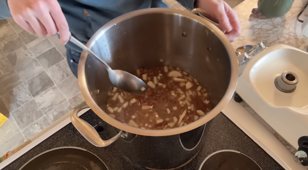 A stainless steel bowl with bean and onion soup in it.