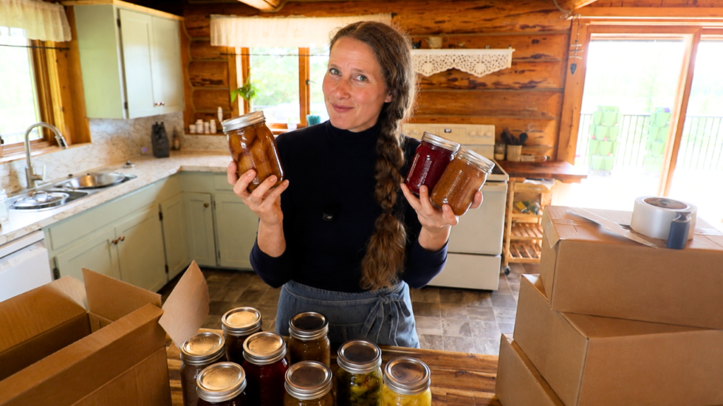 An image of Chelsea standing behind her kitchen island with several jars of home canned food.