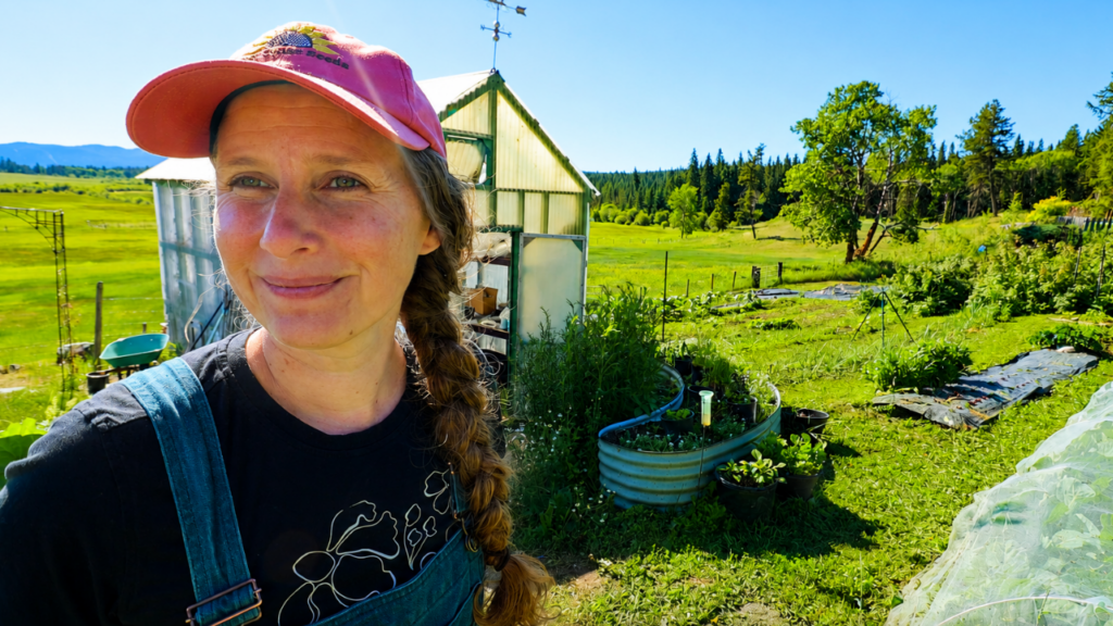 Chelsea standing in front of a row of brassicas under a row cover.