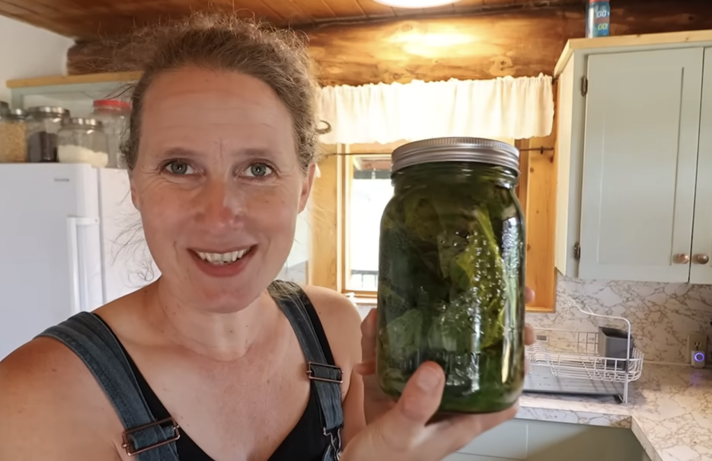 Chelsea holding up a jar of comfrey leaves in olive oil.