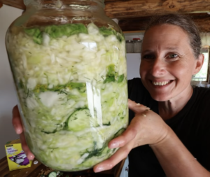Chelsea holding up a gallon jar of crisp dill pickle sauerkraut.